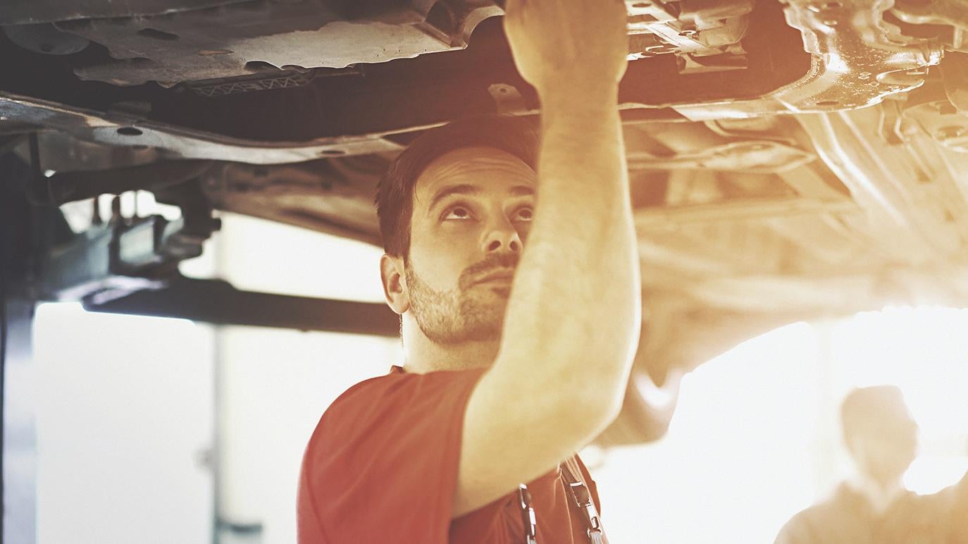 image of a man working under a car